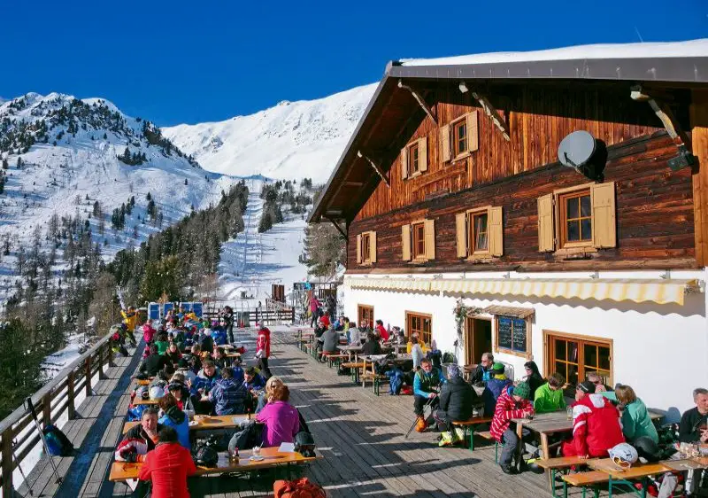 A picturesque view of Furkel-Trafoi ski resort in South Tyrol Italy bustling with winter sports activities featuring a mountain hut and a charming chalet amidst a snowy landscape.
