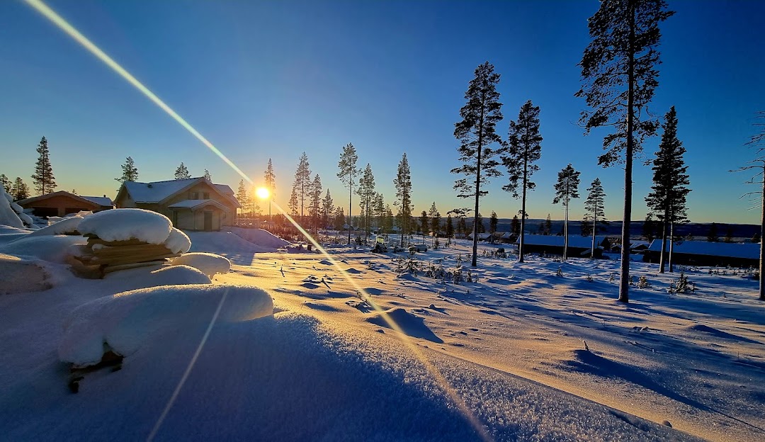 Winter sports enthusiasts enjoying the pristine winter scenery at Idre Himmelfjäll in Sweden, complete with a snowmobile parked nearby at the winter sports centre.
