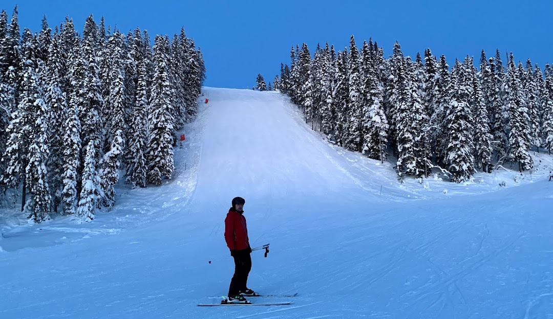 A skier enjoying a run at the Idre Himmelfjäll ski resort in central Sweden, surrounded by snowy slopes and a visible ski lift on a clear winter day.