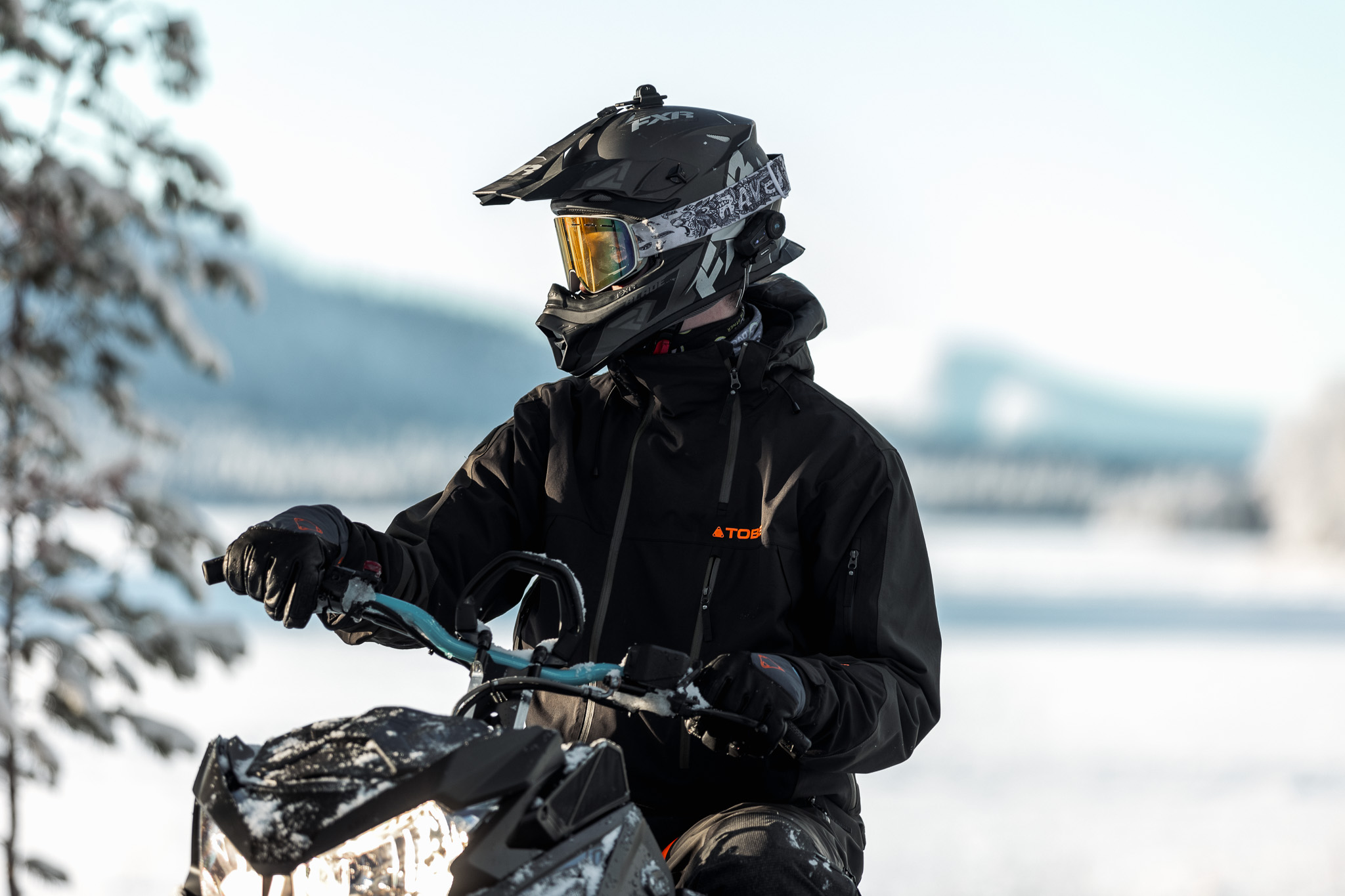 Winter sports enthusiasts enjoy the snowy slopes at Idre Himmelfjäll in Central Sweden. Skiers and snowboarders carve paths alongside a snowmobile, in a picturesque mountain setting.