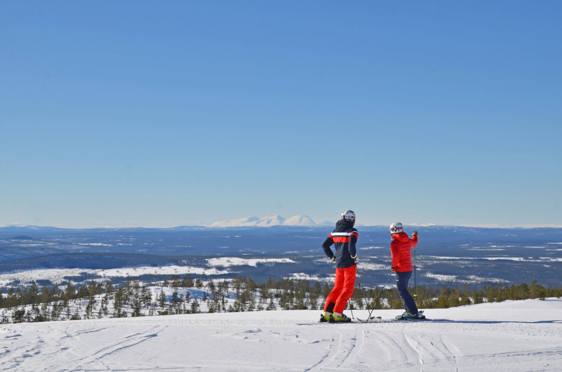 A skier navigating the snowy slopes at Idre Himmelfjäll, a winter sports centre located in Idre, Central Sweden. A chalet and other resort facilities peak out from the majestic wintry landscape.