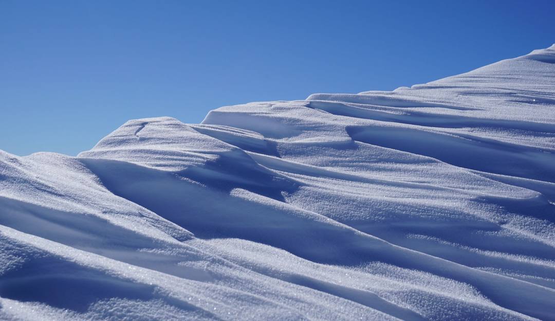 Breathtaking winter scene at Snow Ridge in the Adirondacks, New York, showcasing snowy slopes, a quaint chalet, and people partaking in winter sports.