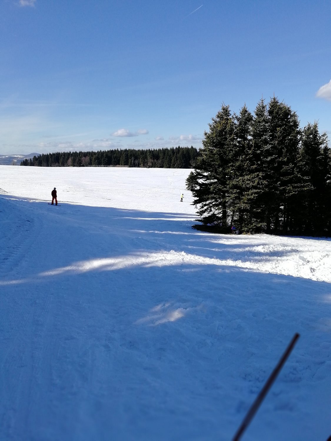 Winter sports scene featuring a skier coming down the slope at Telnice Resort in the Ústí nad Labem Region, Czech Republic with ski lift and challet in the background.