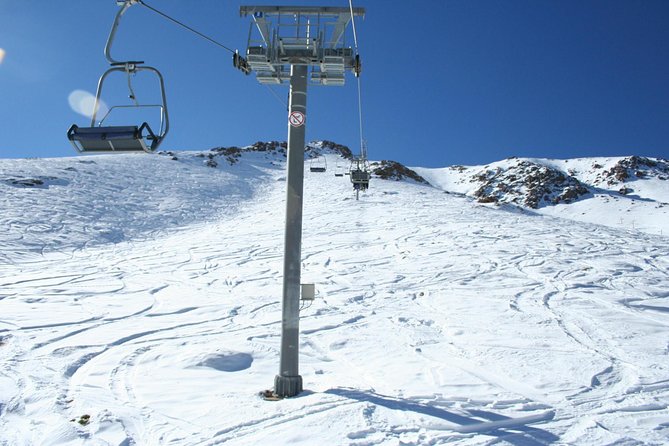 A ski lift is pictured at the bustling Oukaïmeden ski resort in Morocco with a quaint chalet off to the side. Skiers can be seen partaking in winter sports.