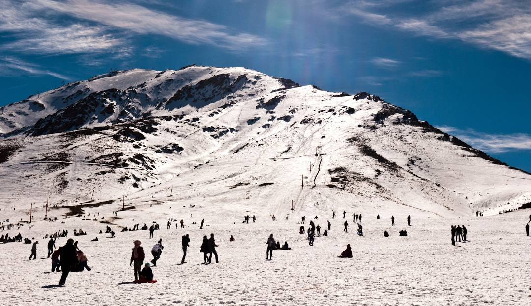 Oukaïmeden in Morocco - a group of people walking across a snow covered mountain.