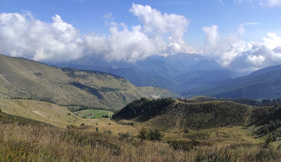Image of a charming chalet nestled in the mountains in Monesi di Triora, Italy. The sky is clear indicating a sunny day. It's a popular location for a ski resort with a mountain bike visible.