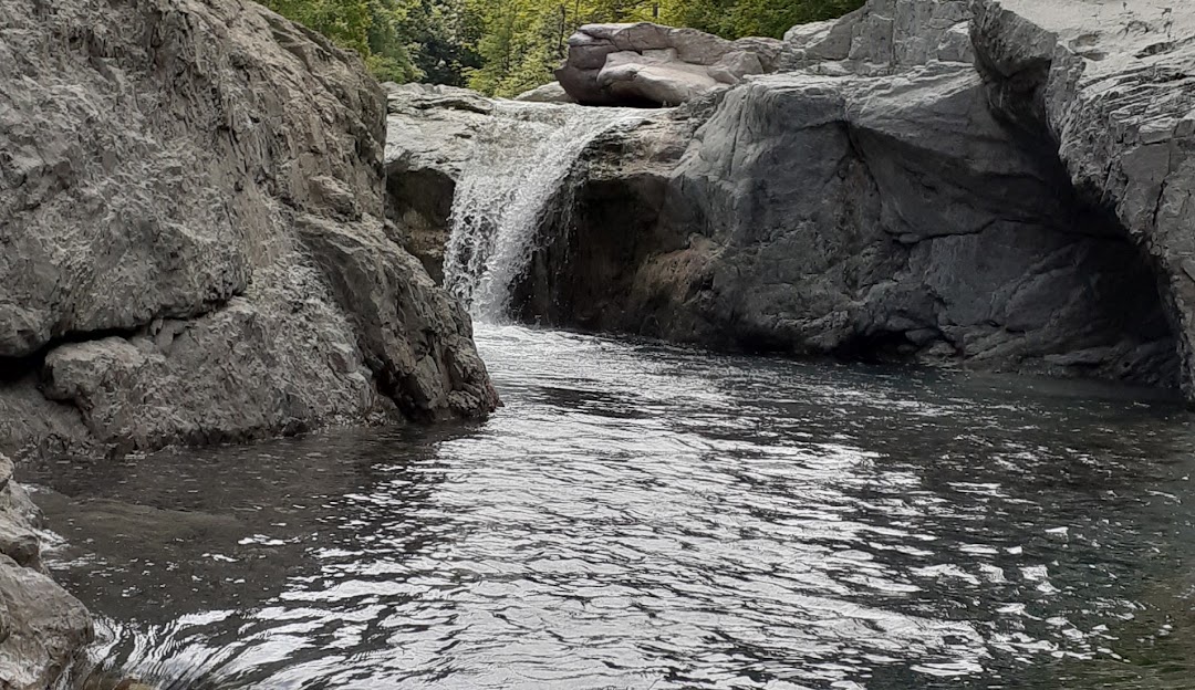 Charming chalet nestled in the shadow of a mountain in Monesi di Triora, Liguria, Italy. A serene lake is also partially visible nearby.
