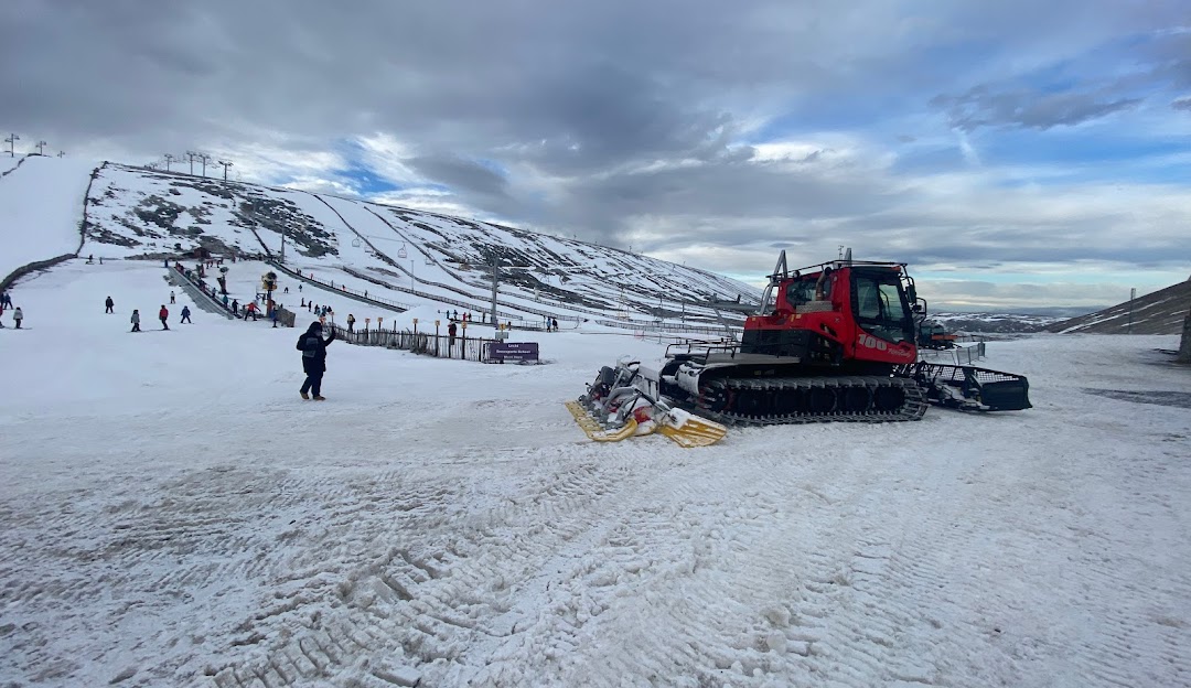 Winter sports scene at Lecht Ski Centre in the Scottish Highlands, featuring a snowmobile, a ski resort and a chalet nestled in a snowy landscape.