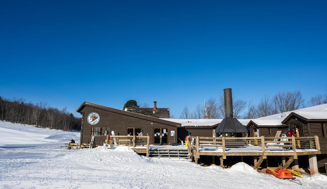 A winter sports scene at Porcupine Mountain in Michigan featuring a ski resort and a central lodge against a backdrop of stunning snowy scenery.