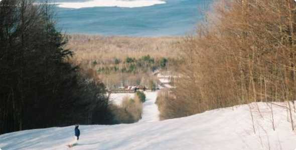 A skier enjoying a winter sports scene at Porcupine Mountain in Ontonagon Michigan USA with a ski resort winter sports centre and chalet in the backdrop.