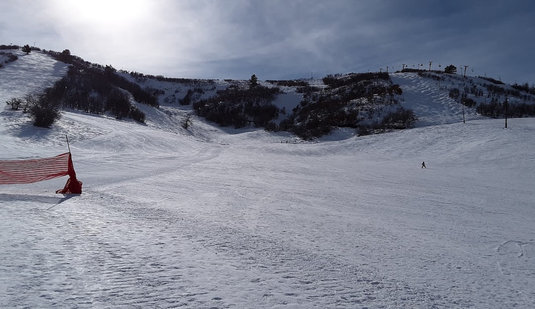 A winter sports scene at Hesperus Ski Area in Colorado USA. A challet and ski resort visible alongside snow-covered slopes with a skier navigating the terrain.