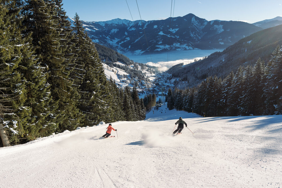 Schmittenhöhe in Austria - a person skiing down a mountain on a sunny day.