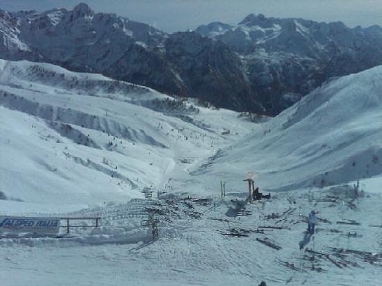 Image of a charming chalet nestled in the snowy landscape of San Simone Ski Resort in Valleve, Bergamo, Italy. The resort is bustling with winter sports enthusiasts.