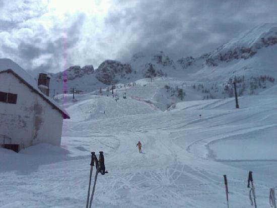 View of a charming chalet within a bustling ski resort in San Simone, Lombardy, Italy. This wintry scene brims with activity from skiers and a lively winter sports center.