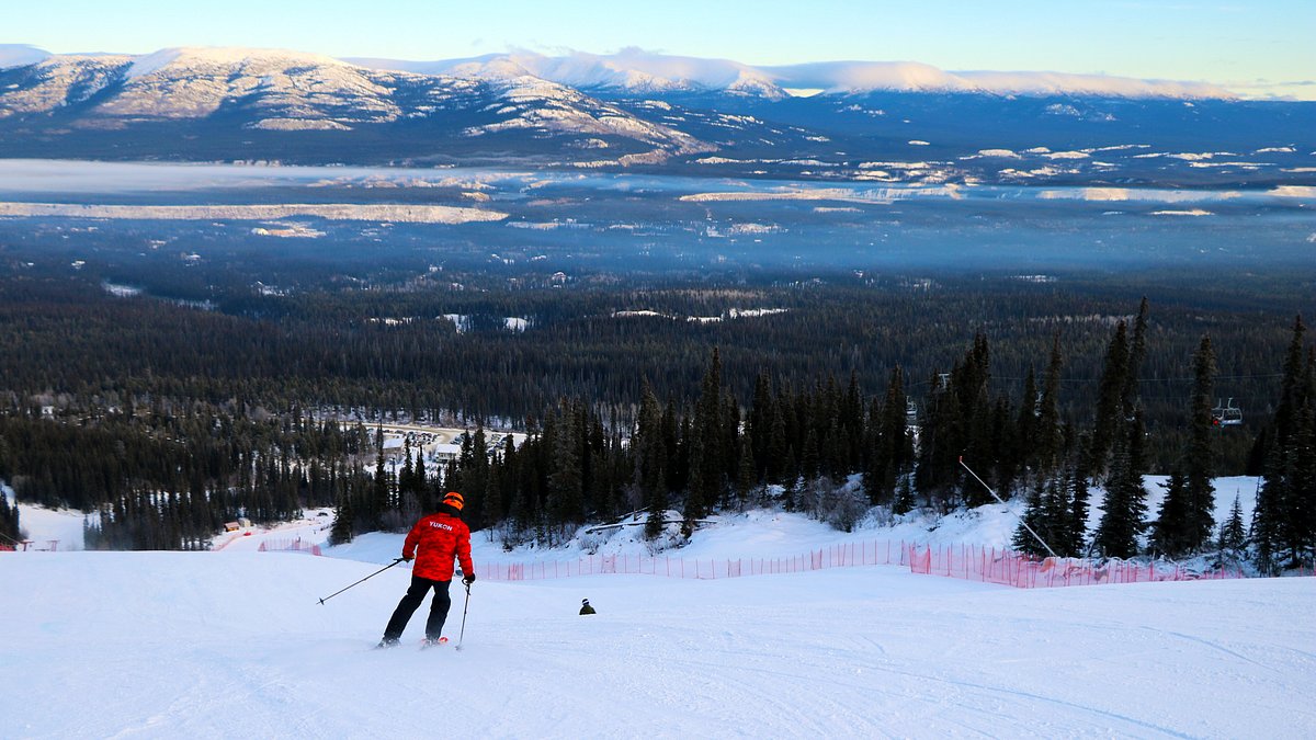 Mount Sima in Canada - a person skiing down a mountain with mountains in the background.