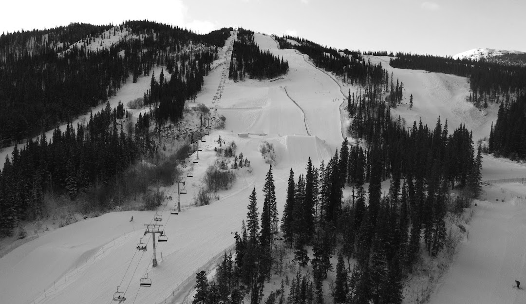 A view of Mount Sima ski resort in Whitehorse Yukon featuring a ski lift ascending snow-covered slopes with a winter sports scene signifying active skiing happening around.