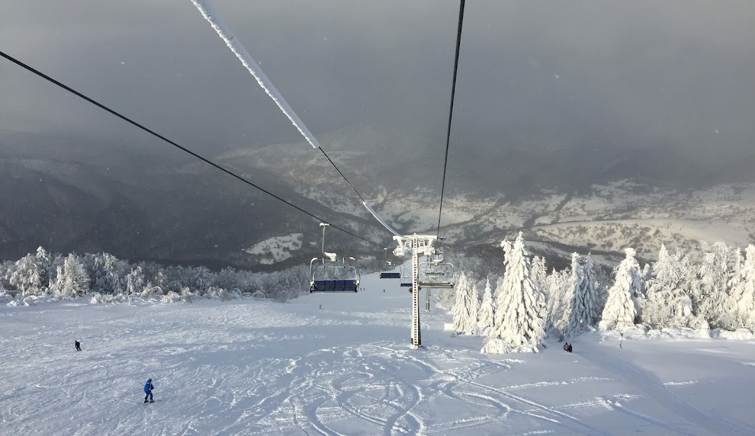 Ski lift and resort at Krasiya in Vyshka, Zakarpattia, Ukraine bustling with winter activities. A skier is descending the snowy slopes near a cozy challet.