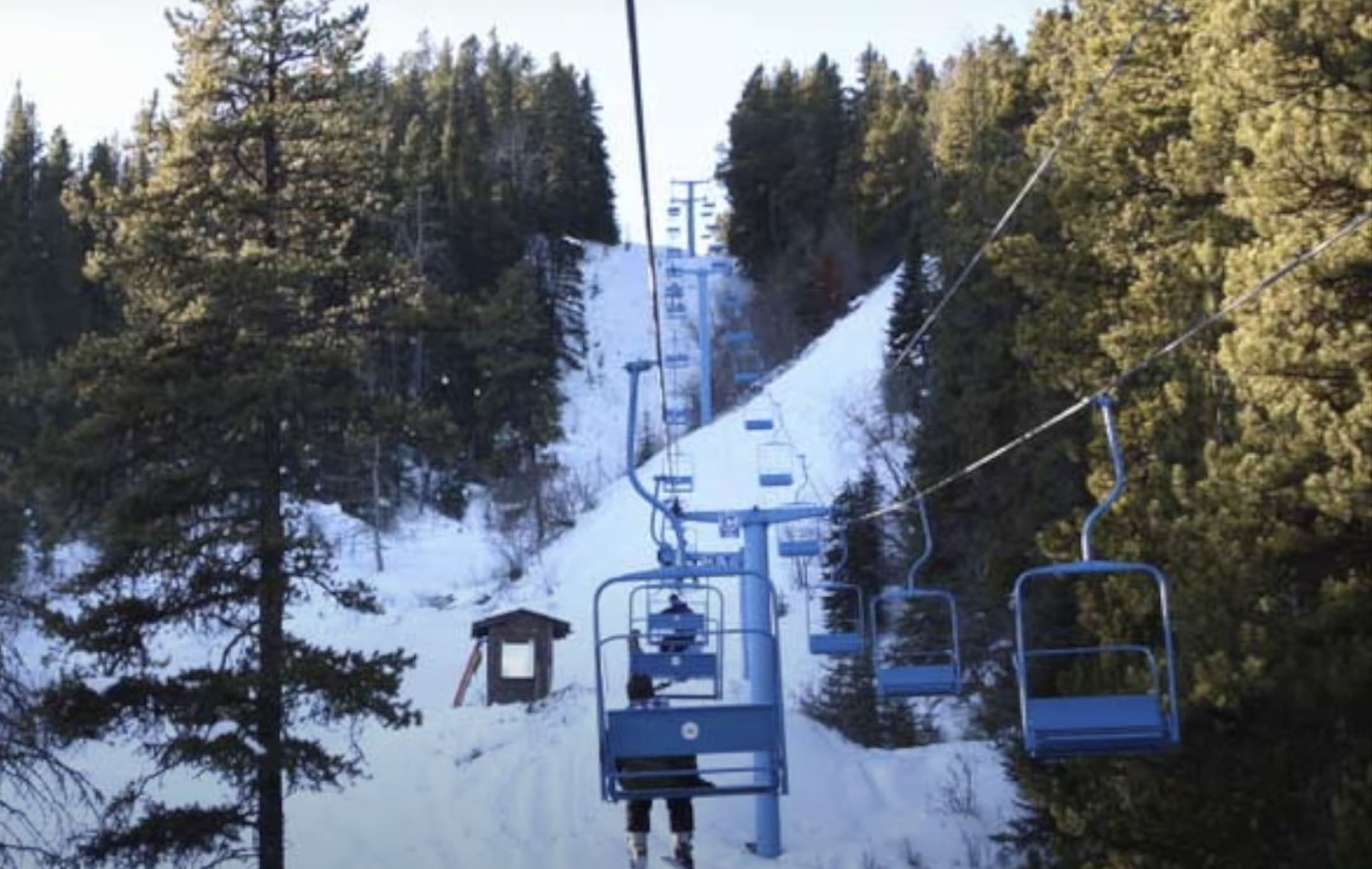 An inviting ski lift in Silver Summit, Yellowhead County, Canada traverses a snow-covered slope bustling with activity. Ski resort features include a cozy chalet amidst a stunning winter sports scene.
