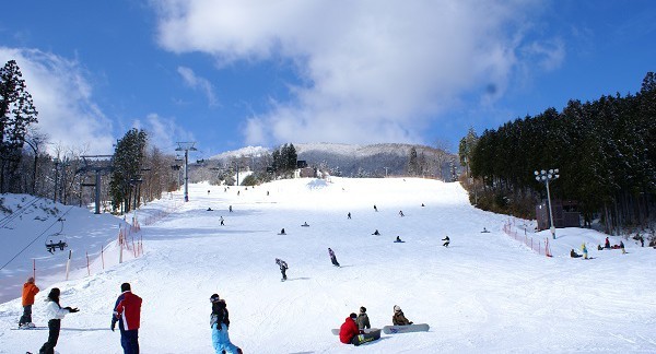 Winter scene at Megahiraonsen Megahira Ski Area in Hiroshima, Japan, featuring a bustling ski resort with skiers, a charming chalet, and stunning snowy landscape.