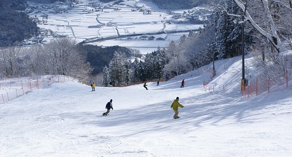 Winter sports scene at Megahiraonsen Megahira Ski Area, Hiroshima, Japan, featuring a ski resort, a winter sports centre, a chalet, and a skier enjoying the snowy slopes.