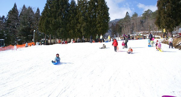 Winter sports scene at Megahiraonsen Megahira Ski Area in Hiroshima, Japan, featuring a bustling ski resort, a charming chalet, and a ski lift.