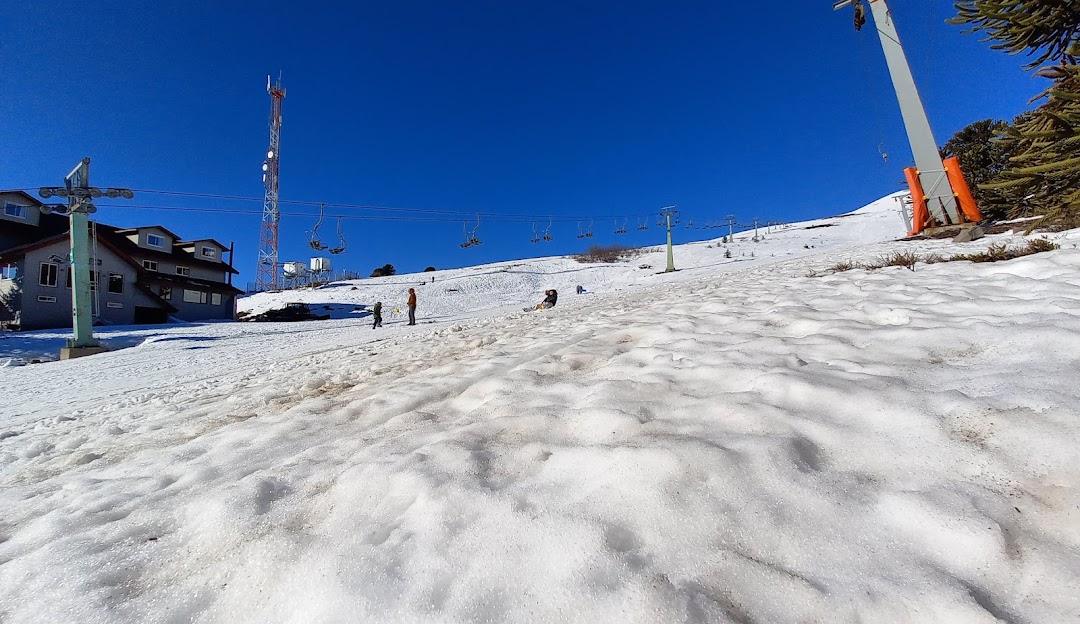 A scenic winter sports scene at Centro de Ski Araucarias - Volcán Llaima in Chile with a ski lift and resort surrounded by pristine white snow and stunning natural beauty.