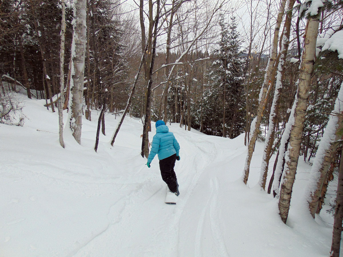 Winter sports scene at Mont Avalanche, Quebec, featuring a skier in action, a challet in the backdrop, and a ski lift visible in the distance.