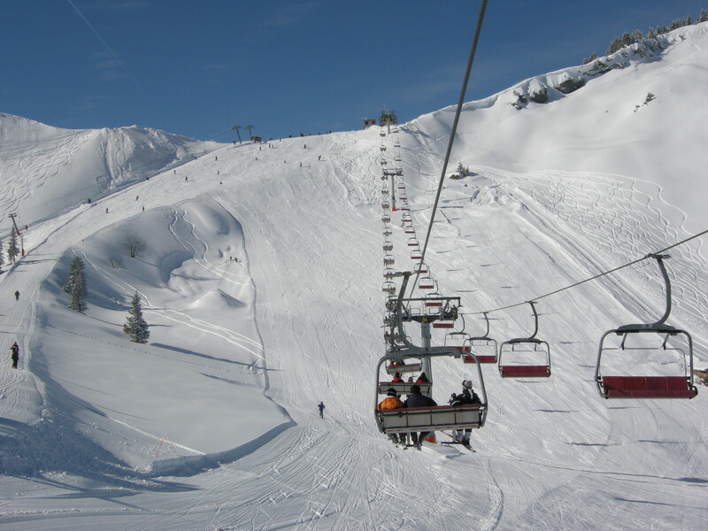 View of the Breitenberg-Hochalpe ski resort in Pfronten Germany featuring a ski lift a chalet snow-covered slopes and skiers enjoying winter sports.