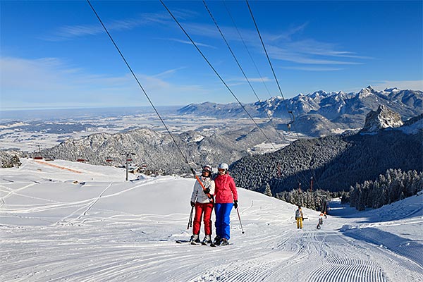 Winter sports scene at Breitenberg - Hochalpe - Pfronten ski resort in Bavaria, Germany, featuring a ski lift, a challet, and a family enjoying skiing.