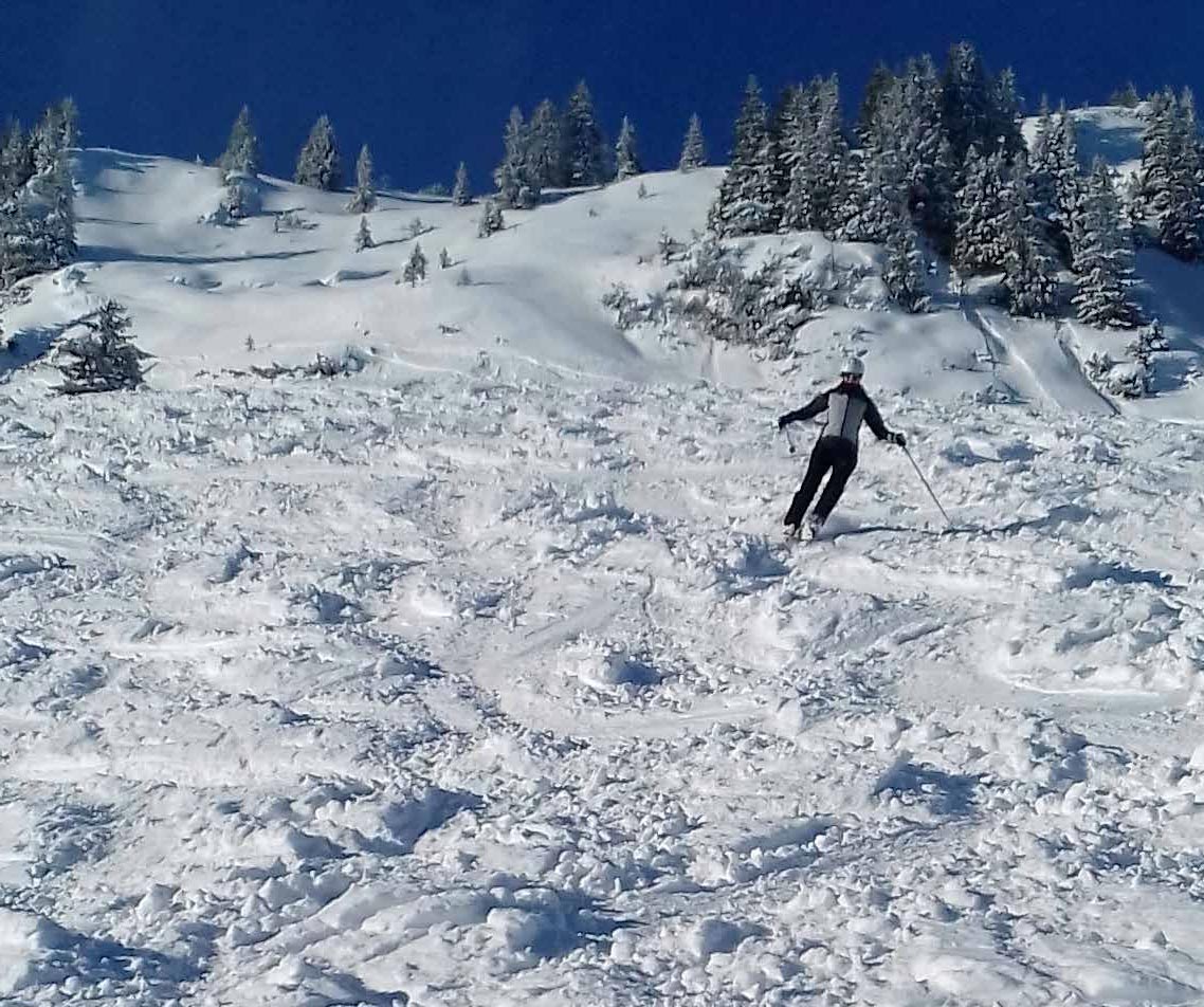 A skier navigating a snowy slope in Breitenberg - Hochalpe - Pfronten, Bavaria, Germany, with a charming chalet in the backdrop and other winter sports enthusiasts nearby.