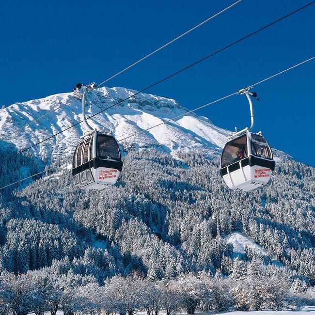 Ski lift amidst scenic winter landscape in Breitenberg - Hochalpe - Pfronten, Germany. Ski resort and chalet visible, surrounded by snow-white terrain for winter sports.