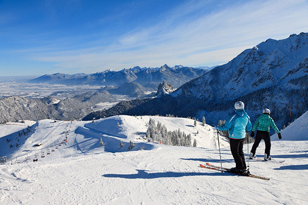 Winter sports scene at Breitenberg - Hochalpe - Pfronten ski resort in Bavaria Germany featuring a skier near a chalet and a ski lift.