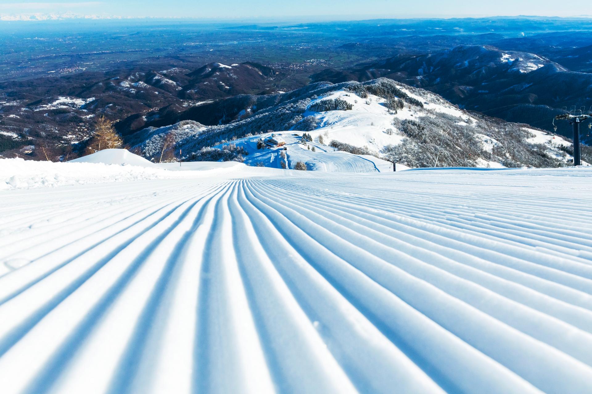 A skier carving down the snow-covered slopes at Lurisia Monte Pigna a ski resort in Italy. Breathtaking winter scenery in the background completes this dynamic winter sports image.