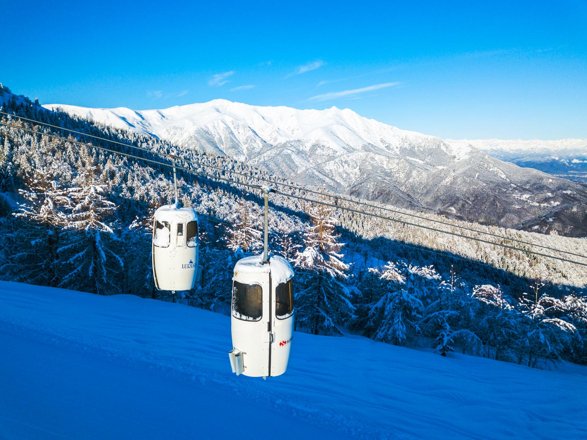 A winter sports scene at Lurisia Monte Pigna in Piedmont Italy featuring stunning winter scenery with skiers using a ski lift amidst a picturesque ski resort.