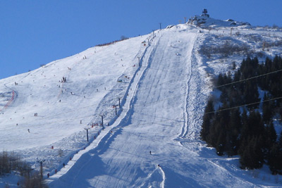 A skier descends a slope at Lurisia Monte Pigna ski resort in Piedmont Italy. The scene includes a snowy mountainside and a charming challet nearby.