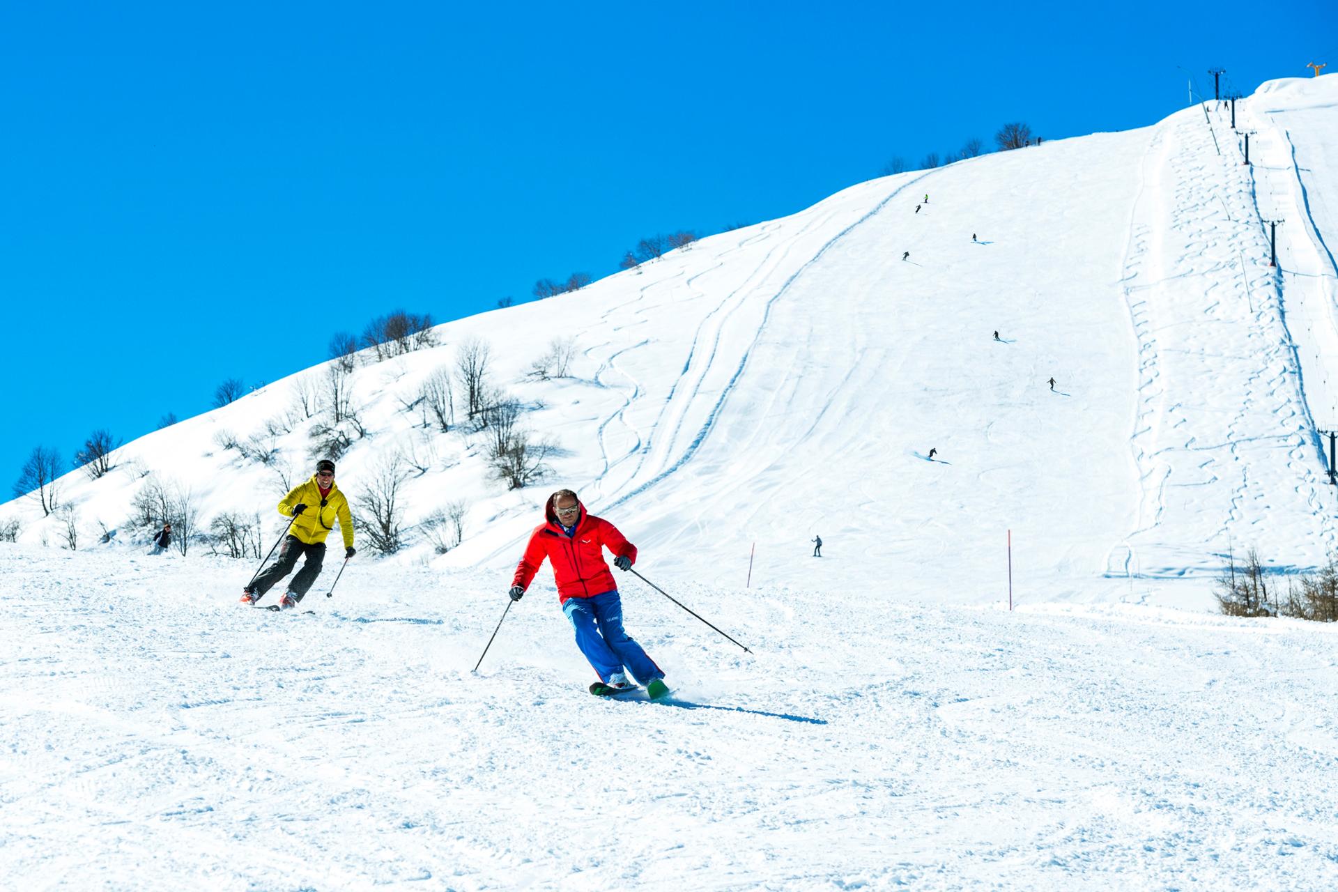 Winter scene at Lurisia Monte Pigna in Piedmont, Italy, featuring a skier on the slopes of the ski resort, with a charming chalet in the background.