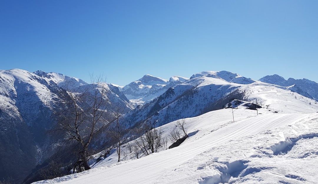 Charming chalet nestled in Lurisia Monte Pigna's stunning winter landscape in Piedmont, Italy. A bustling ski resort visible amidst the serene, snowy scenery.