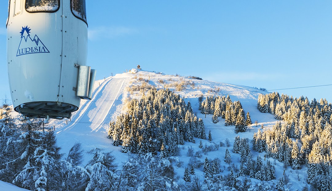 View of Lurisia Monte Pigna ski resort in Piedmont Italy. Features a chalet ski lift and the winter sports centre amidst the stunning winter scenery.