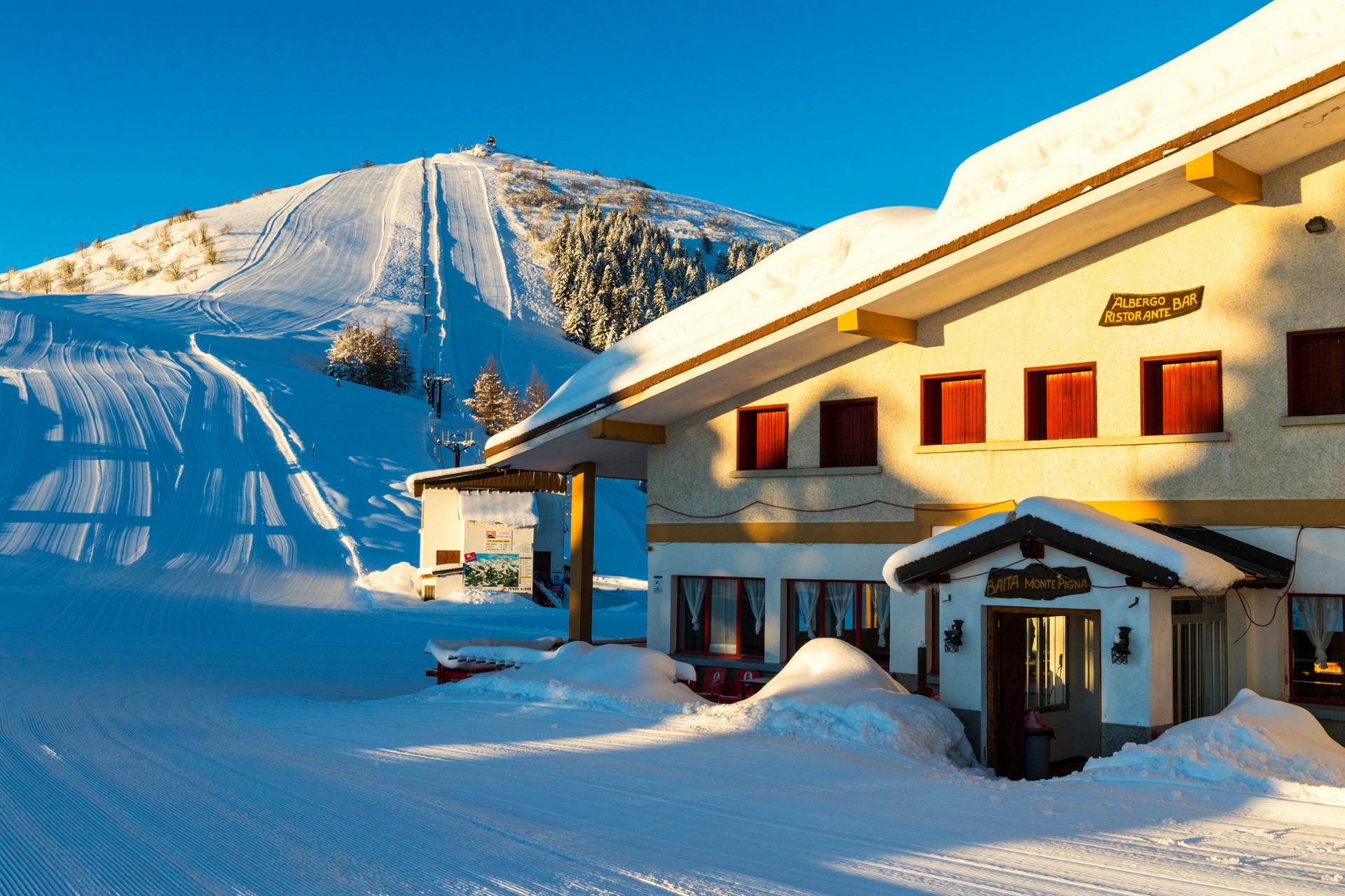 Winter scene at Lurisia Monte Pigna in Piedmont, Italy, depicting the ski resort covered in snow, showcasing winter sports activities amidst stunning scenery.