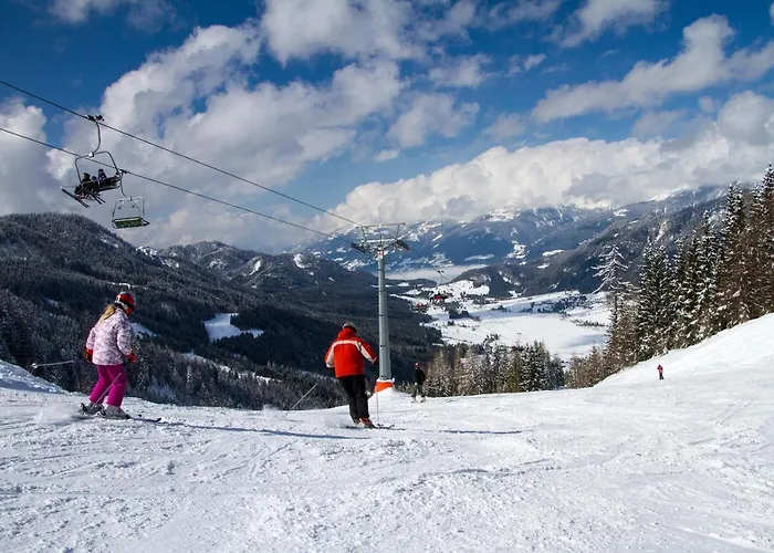 Winter scene at Naggler Alm in Austria, showcasing a bustling ski resort with a ski lift in operation. A skier is gliding down the snowy slopes, with a cozy chalet visible in the backdrop.