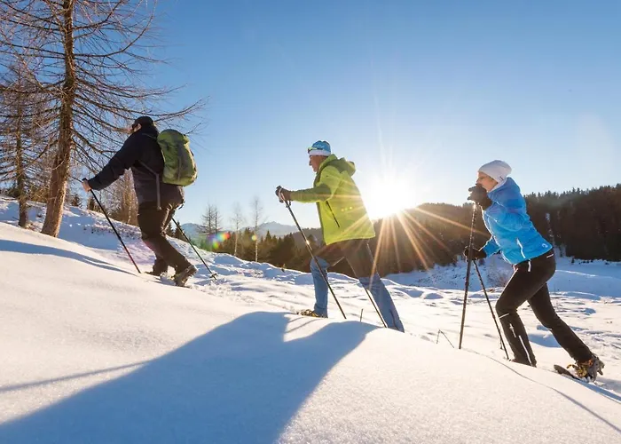 Winter sports scene at Naggler Alm, Austria, with a family and group of people skiing amidst stunning snow-covered scenery.