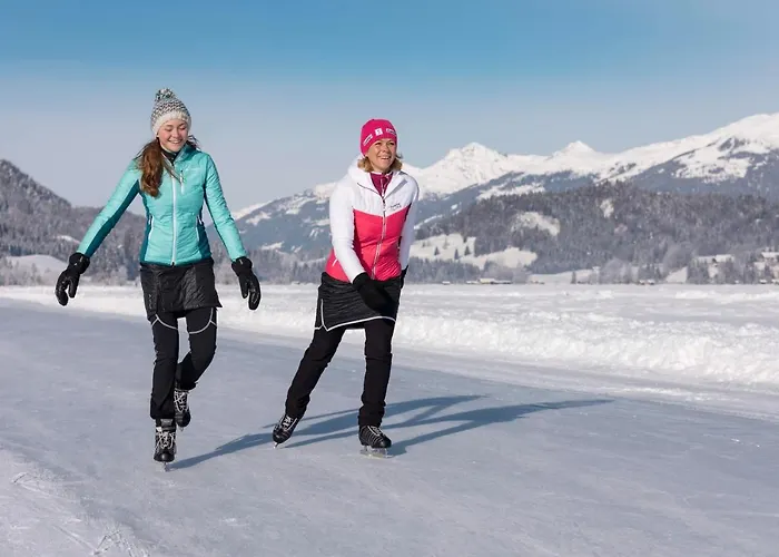 A winter sports scene at Naggler Alm in Naturpark Weissensee, Austria, featuring skiers, possibly a family, gliding down the snowy slopes amidst a serene setting.