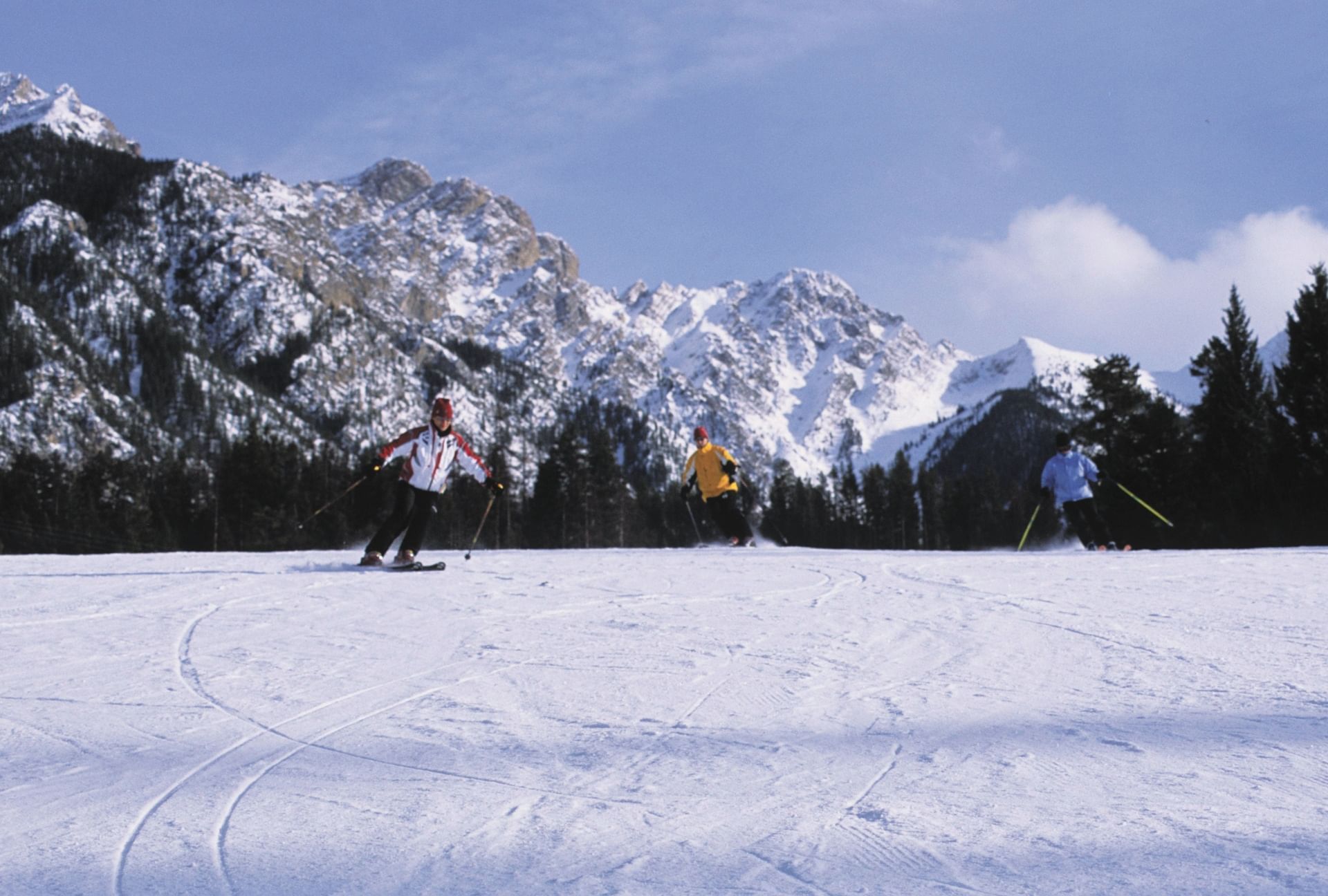 Winter sports scene at Fairmont Hot Springs in British Columbia, Canada showcasing a bustling ski resort with families and groups of people enjoying skiing.