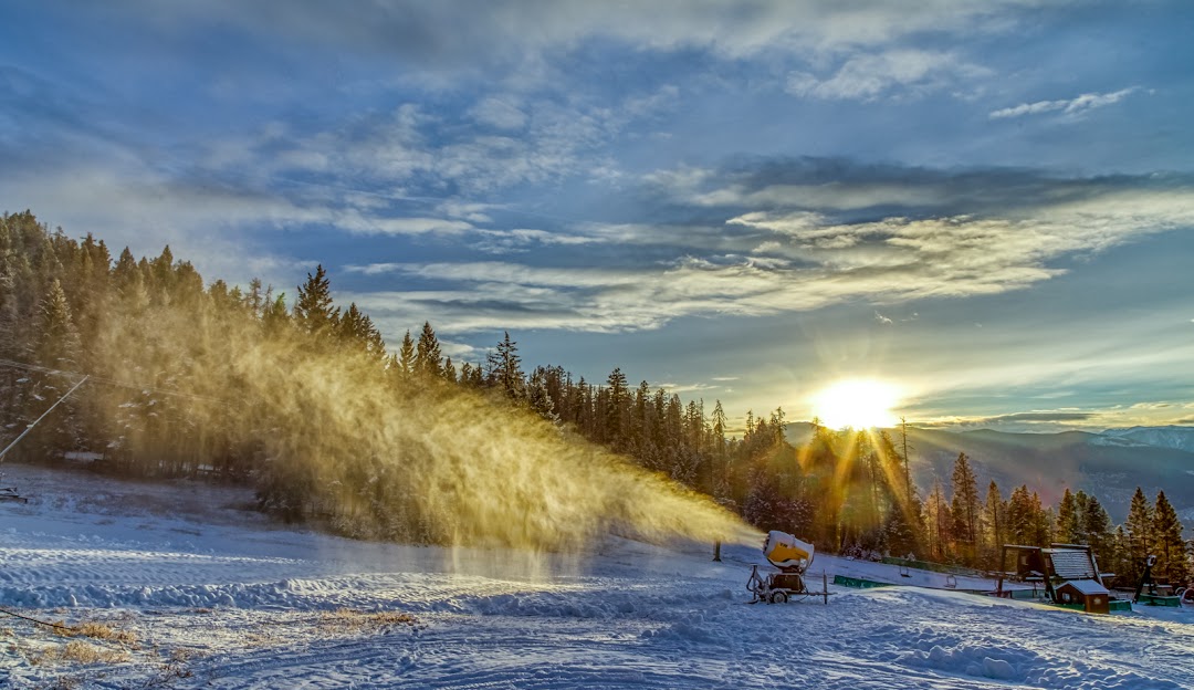Winter sports scene at Fairmont Hot Springs in British Columbia Canada featuring untouched snow a snowmobile in the distance and the ski lift of a resort.