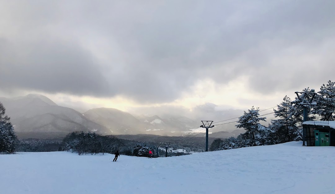 A picturesque winter scene in Numajiri, Tōhoku, Japan showcasing a vibrant ski resort tucked amidst majestic mountains, perfectly blanketed in soft snow, offering a wonderful setting for winter sports.
