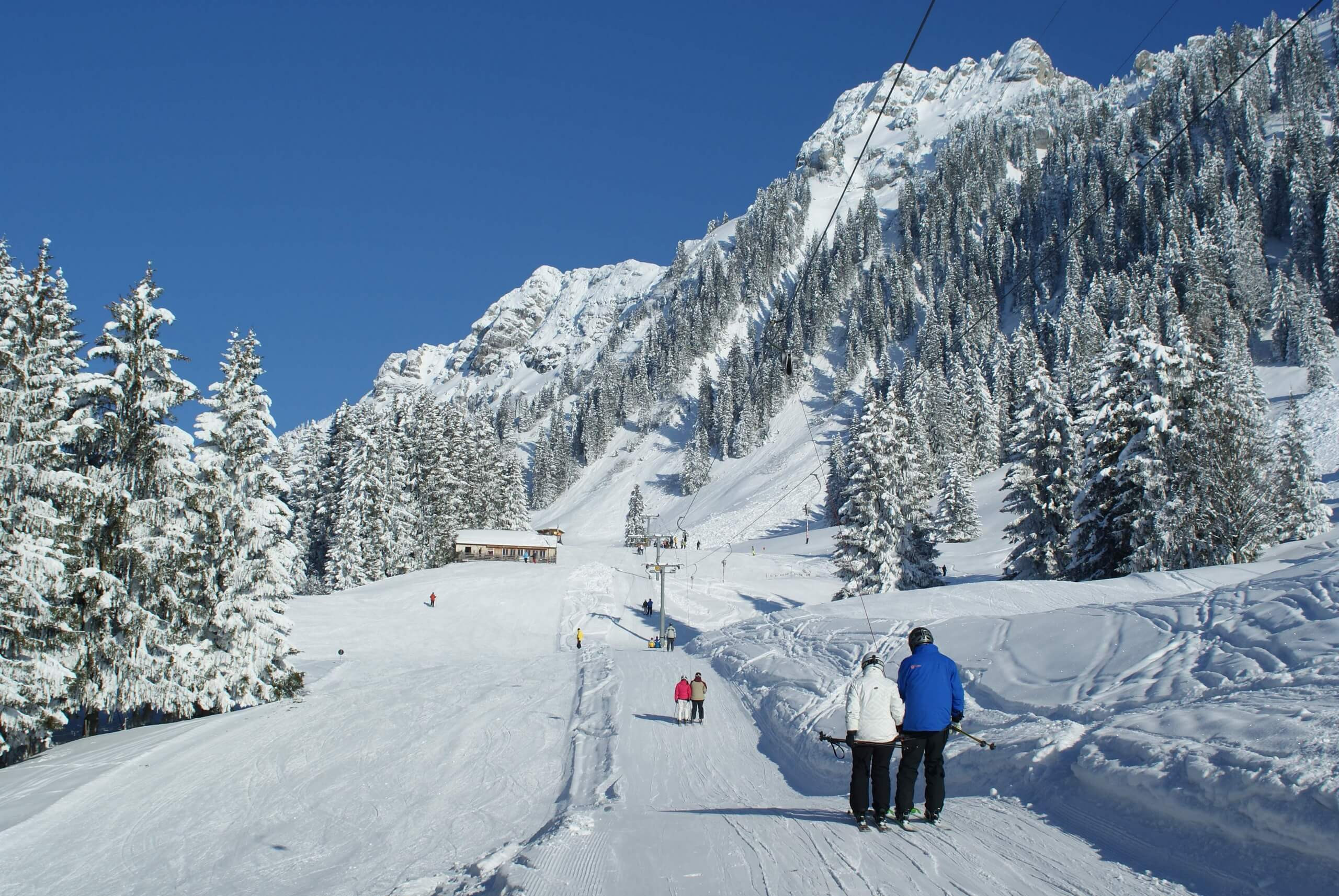 Winter sports scene at Schwanden - Sigriswil in Bern, Switzerland, featuring a bustling ski resort with a ski lift and a charming chalet nestled amidst snowy terrain.