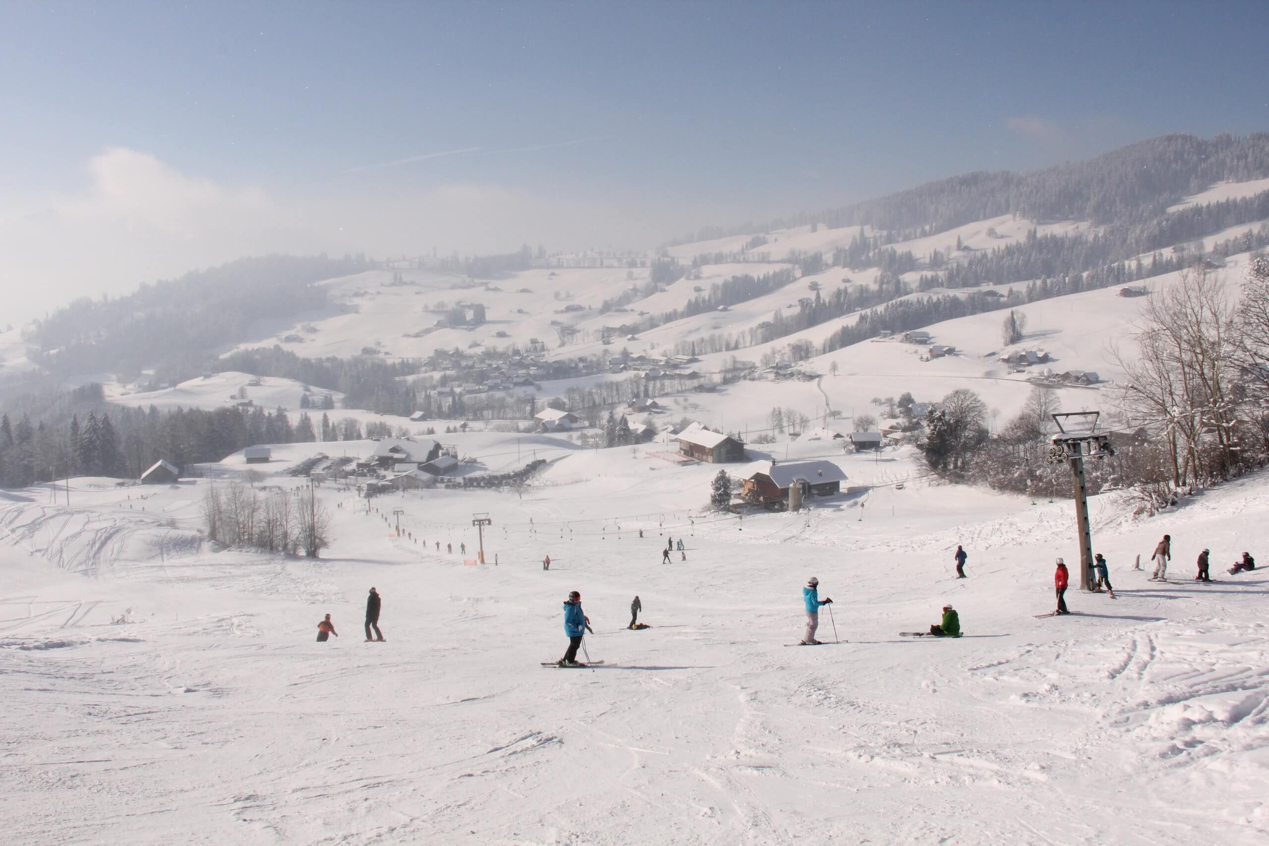 Winter sports scene at Schwanden - Sigriswil in Bern, Switzerland featuring a ski resort, a chalet, and stunning winter scenery near Lake Thun.