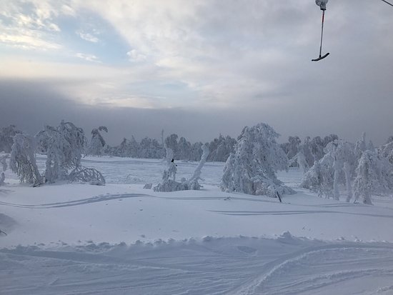 Ski resort at Adzhigardak, Asha, Russia featuring skiers enjoying winter sports. A ski lift is also visible operating amidst the snowy landscape.