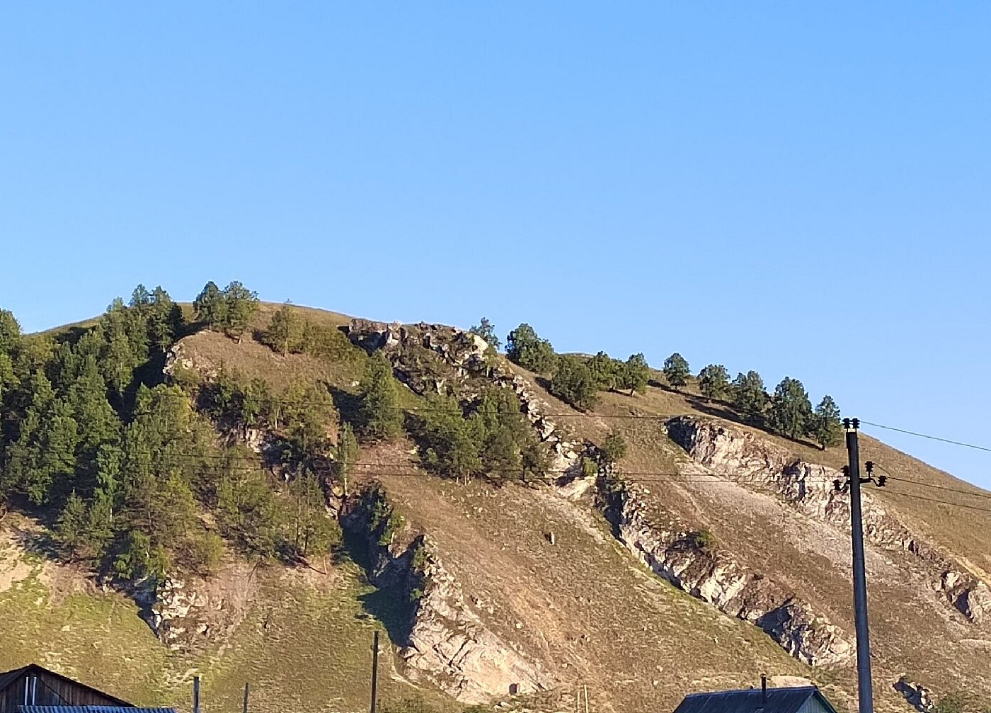 Adzhigardak in Ural Federal District - a view of a mountain with houses and trees.