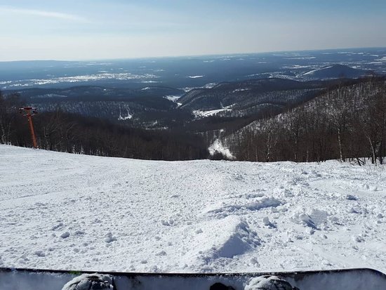Winter sports enthusiasts enjoying a day on the snow-covered slopes at Adzhigardak Ski Resort in Asha, Russia. A chalet nestles at the foot of the stunning Ural mountains.